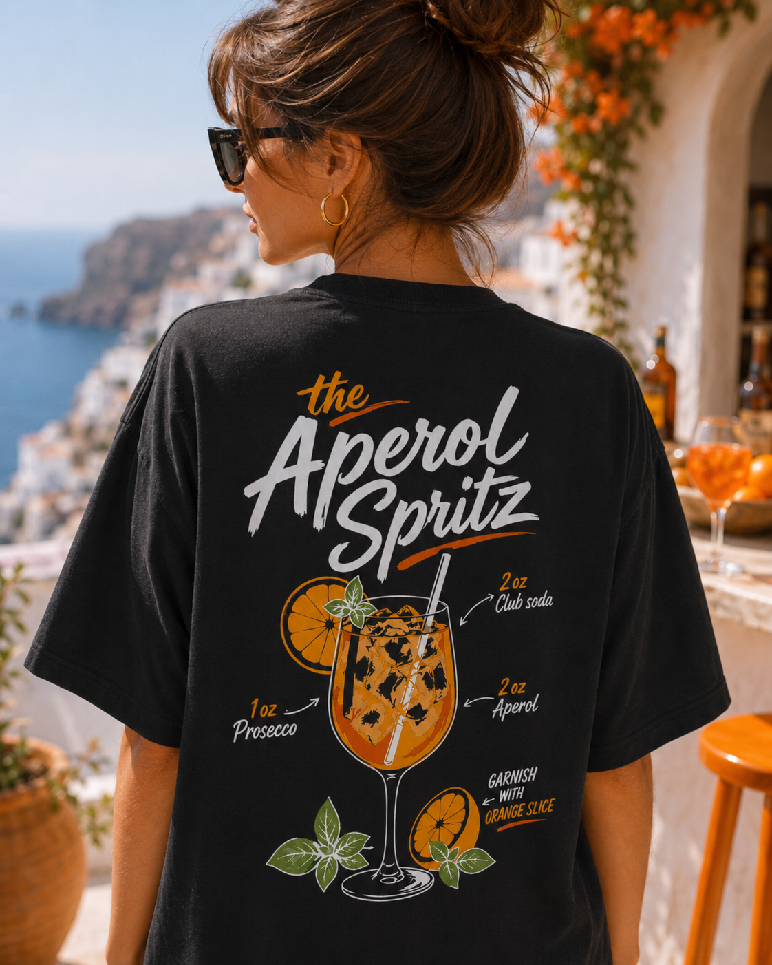 Model feminin purtand tricou negru Spritz State Tee pe terasa cu vedere la mare